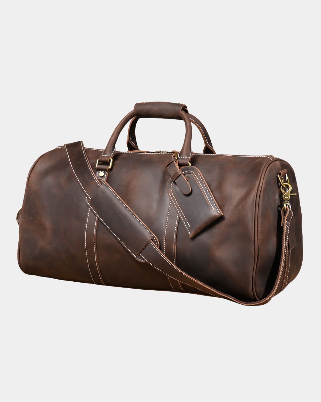 Angled view Men dark brown crazy horse leather duffel bag with luggage tag and crossbody strap by Hudson & Tate.