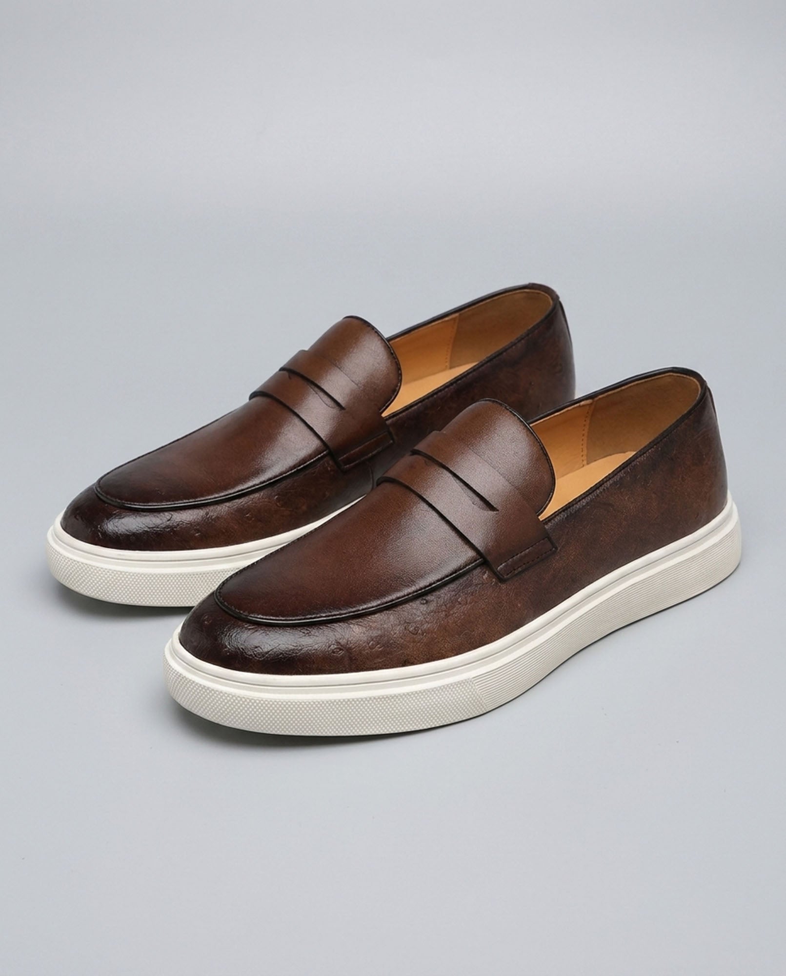 Pair of Belmont men's brown penny loafer sneakers with off-white cupsole on grey background