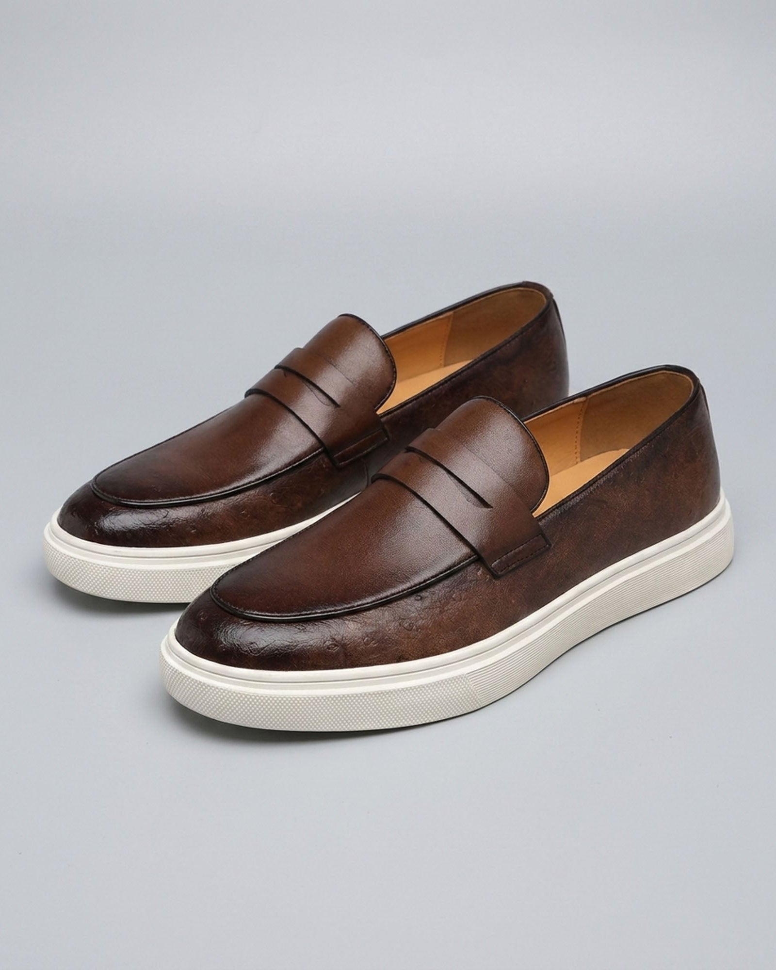 Pair of Belmont men's brown penny loafer sneakers with off-white cupsole on grey background