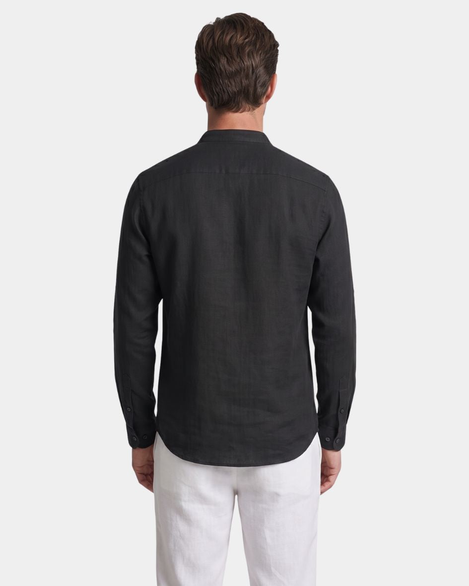 Man wearing a dark gray long-sleeve shirt and white pants on a light gray background