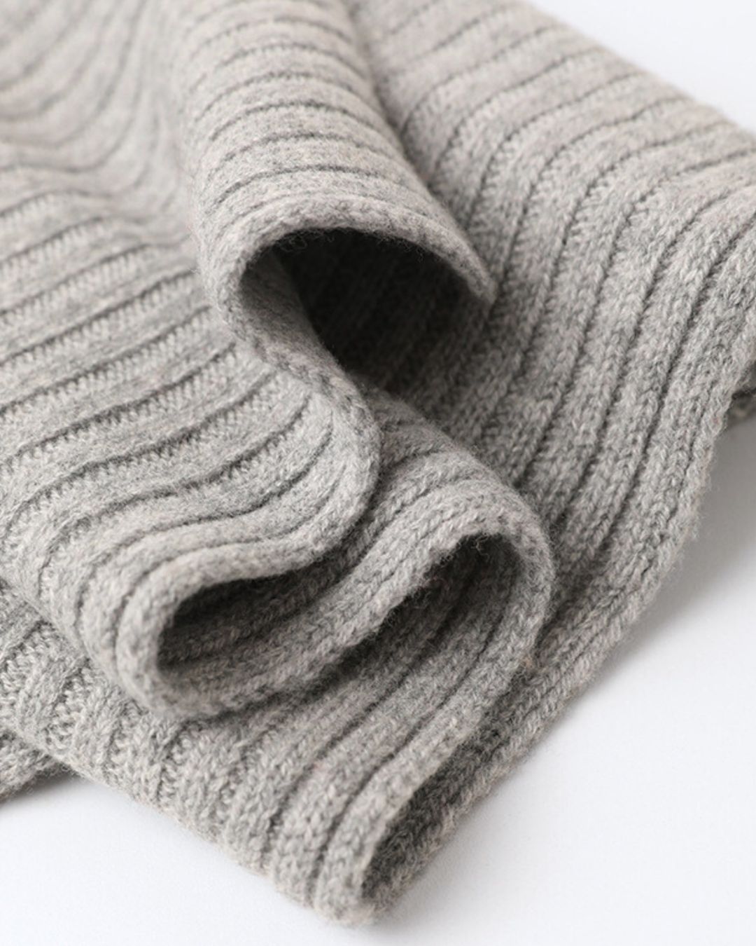 Close-up of a soft, light grey cashmere winter scarf featuring a textured ribbed knit design.
