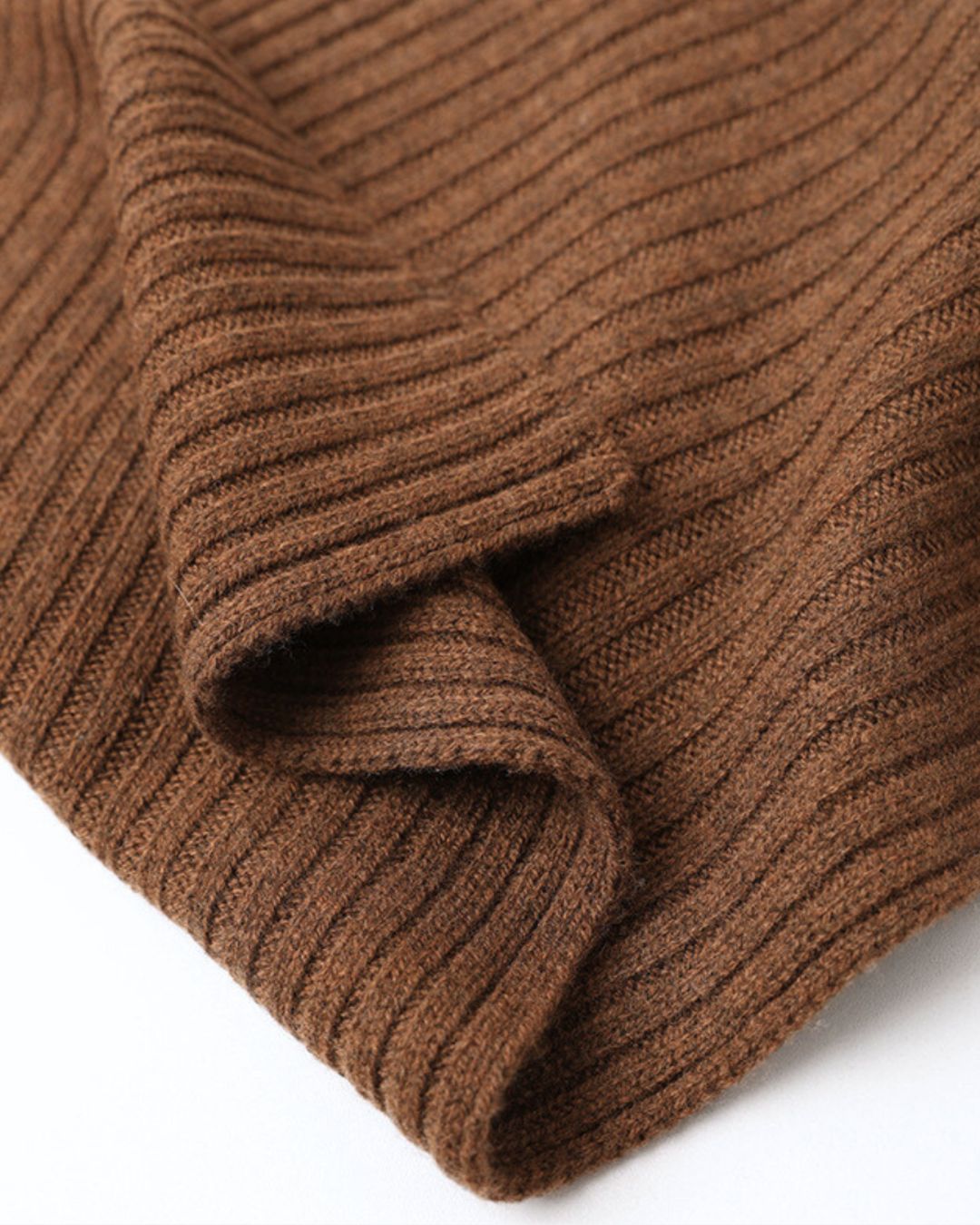 Close-up of a soft, brown cashmere winter set featuring a ribbed knit texture and folded fabric detail.