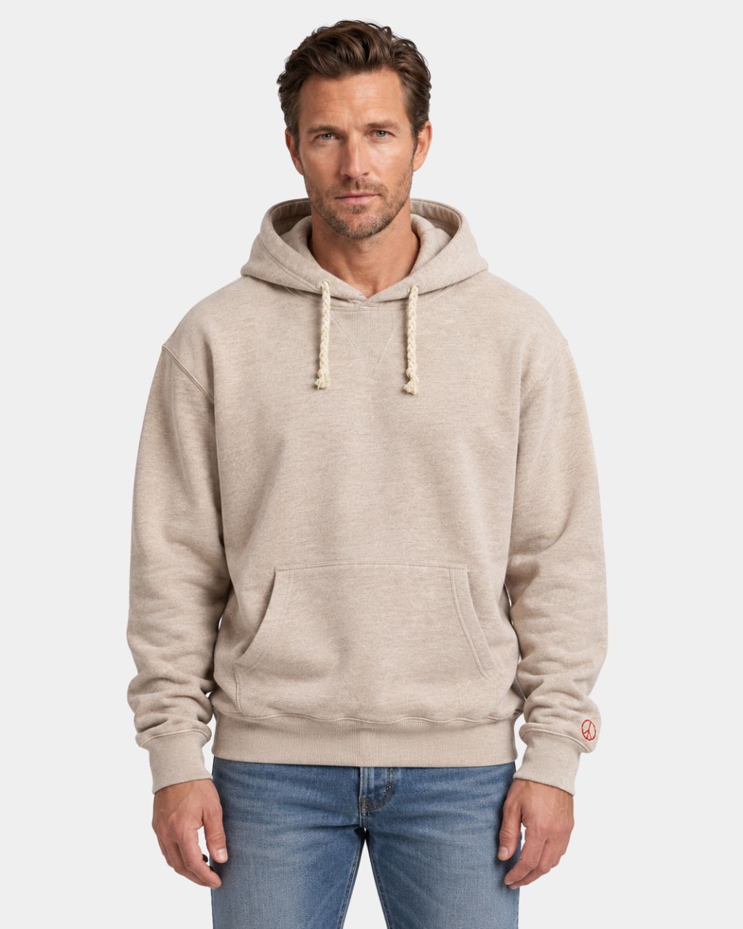 Beige oversized cotton pullover hoodie with drawstring hood, kangaroo pocket, and embroidered peace symbol on sleeve.