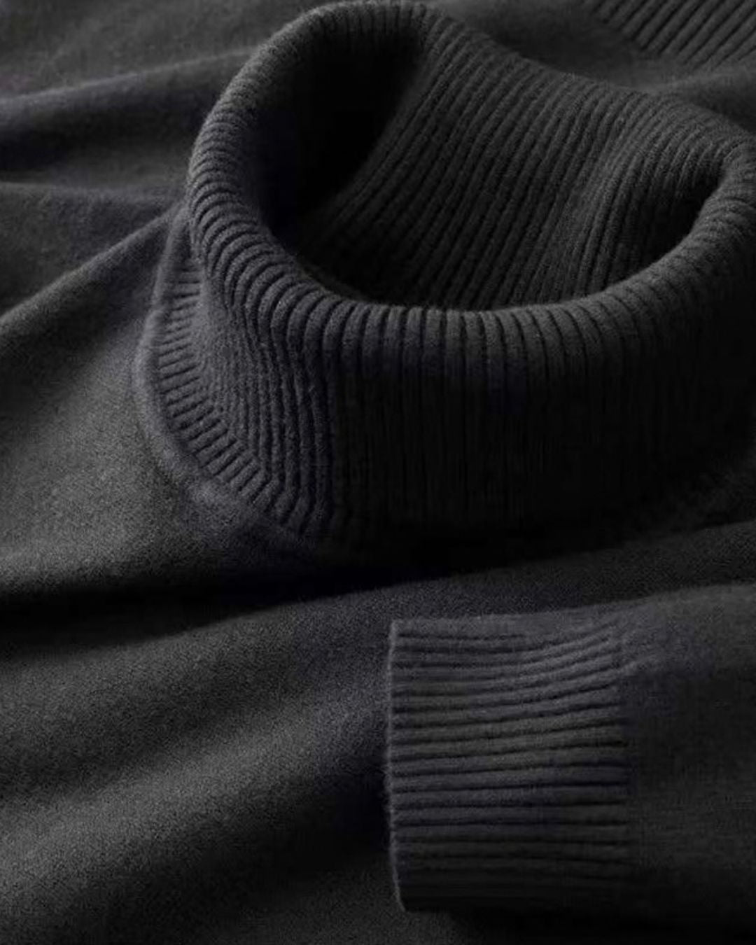 Close-up of a black men's turtleneck sweater featuring a soft knit texture and ribbed collar and cuff detailing.