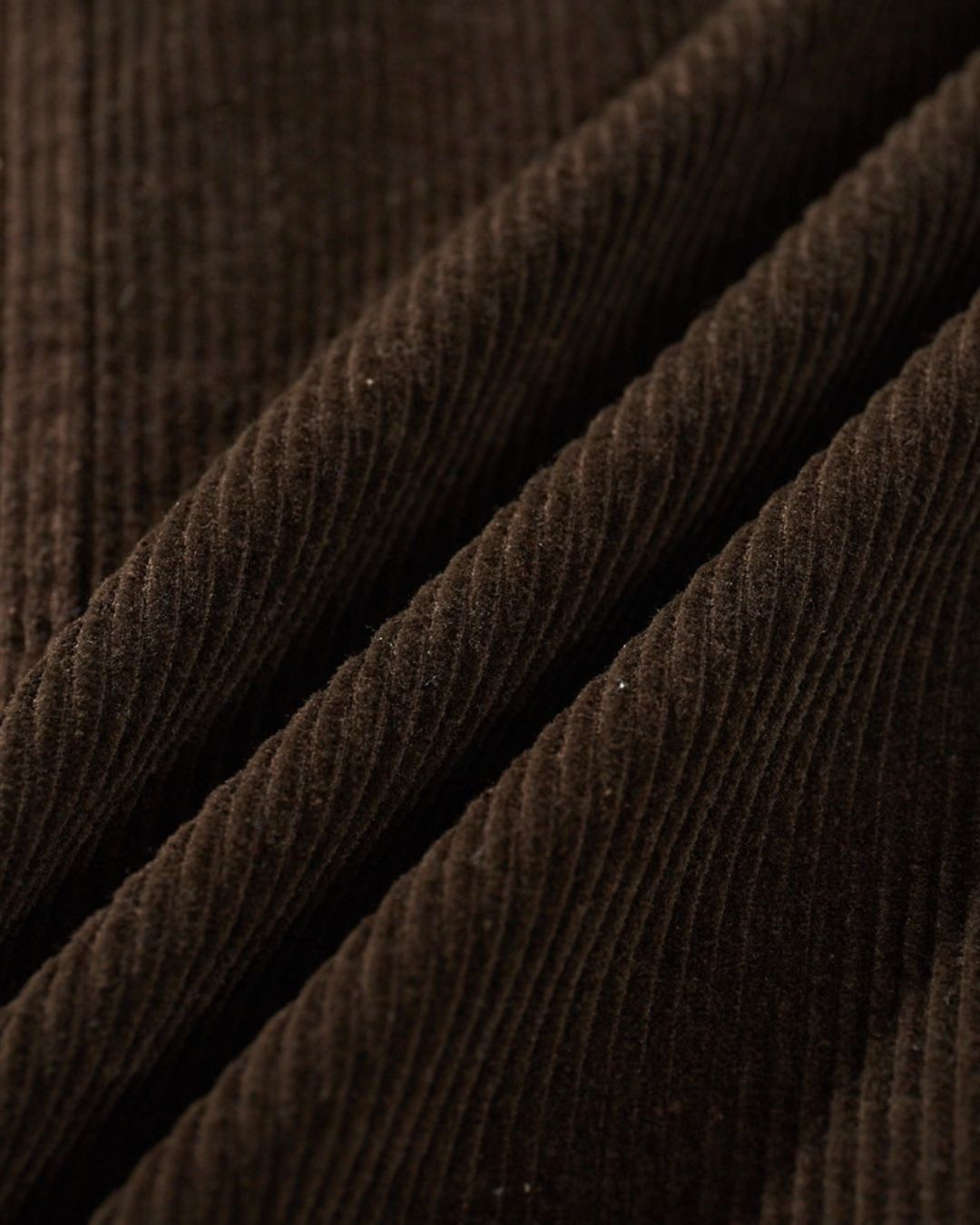Close-up of soft, brown ribbed cotton corduroy fabric with a textured, enzyme-washed finish.
