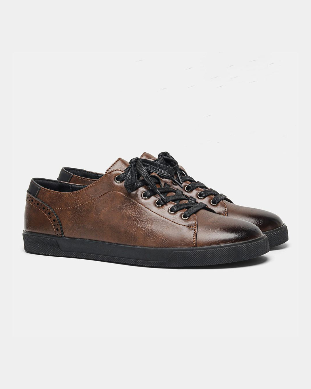 Brown low top dress sneakers with burnished faux leather, black laces, brogue heel detailing, and a flat black rubber sole.