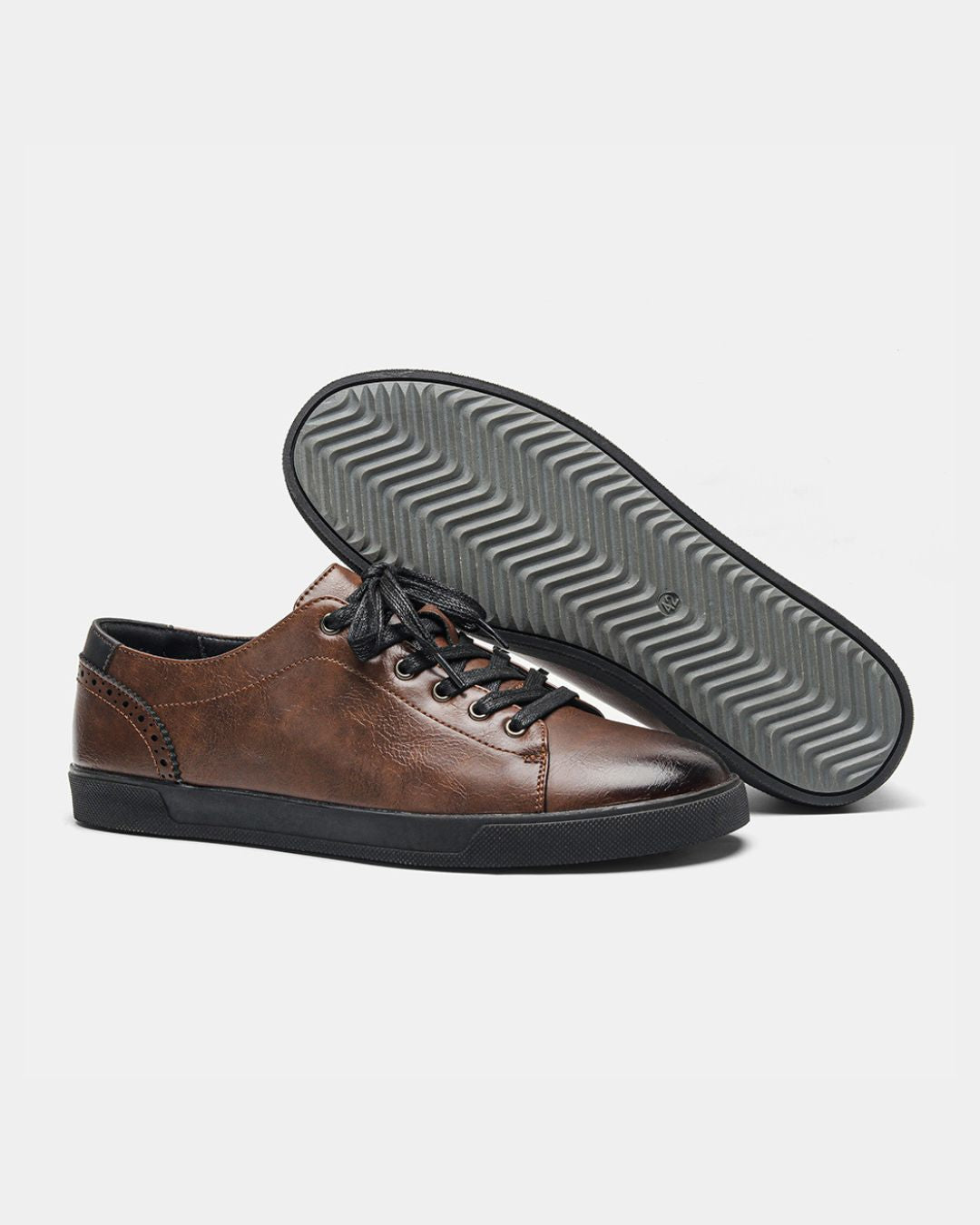 Brown low-top dress sneakers with brogue heel detailing, black laces, and a textured black rubber sole.