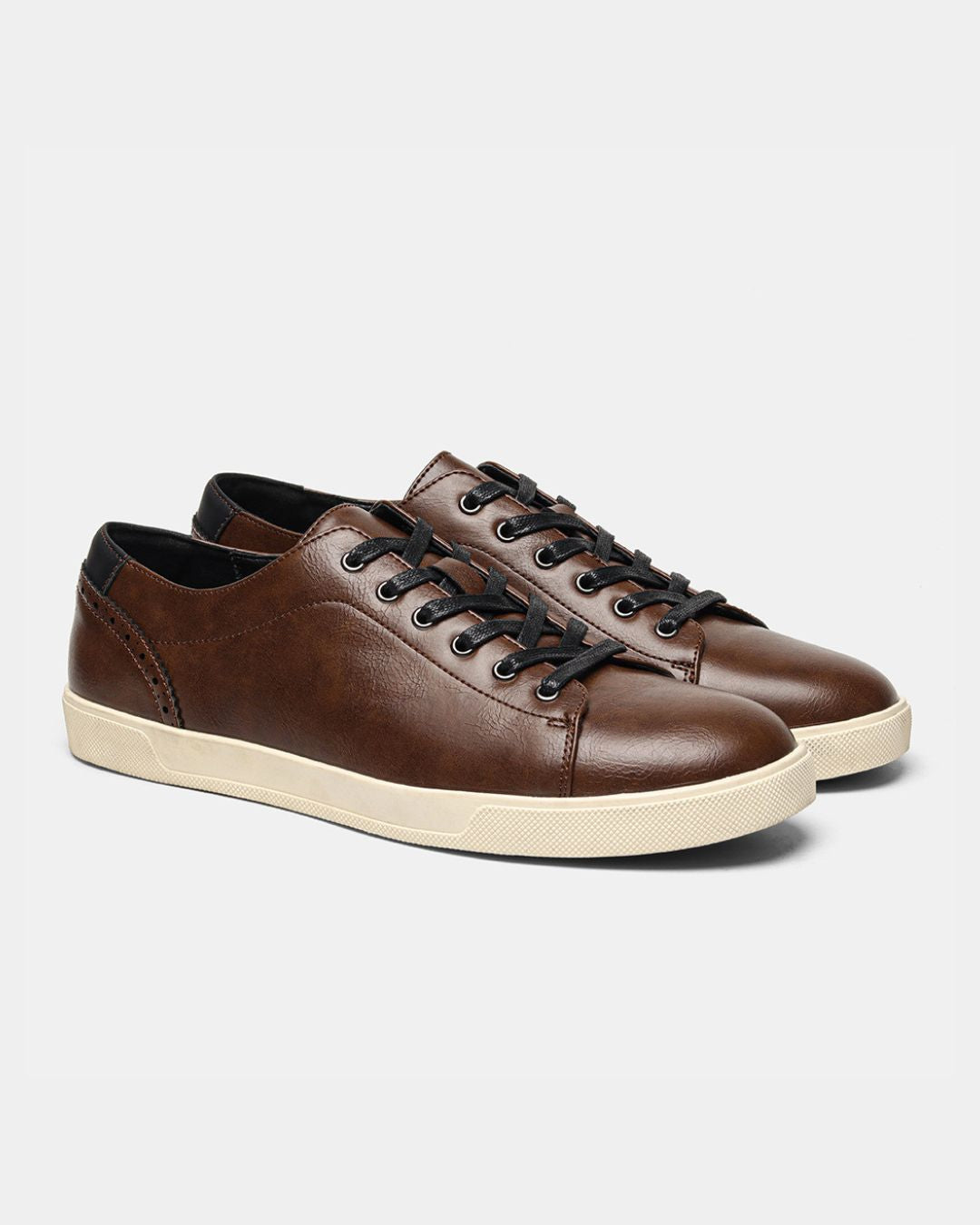 Brown low-top dress sneakers with black laces, brogue heel detailing, and a cream rubber sole.