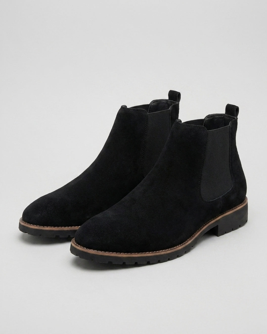 Black suede men's Chelsea boots with elastic side panels, rounded toes, and durable lugged rubber outsoles.