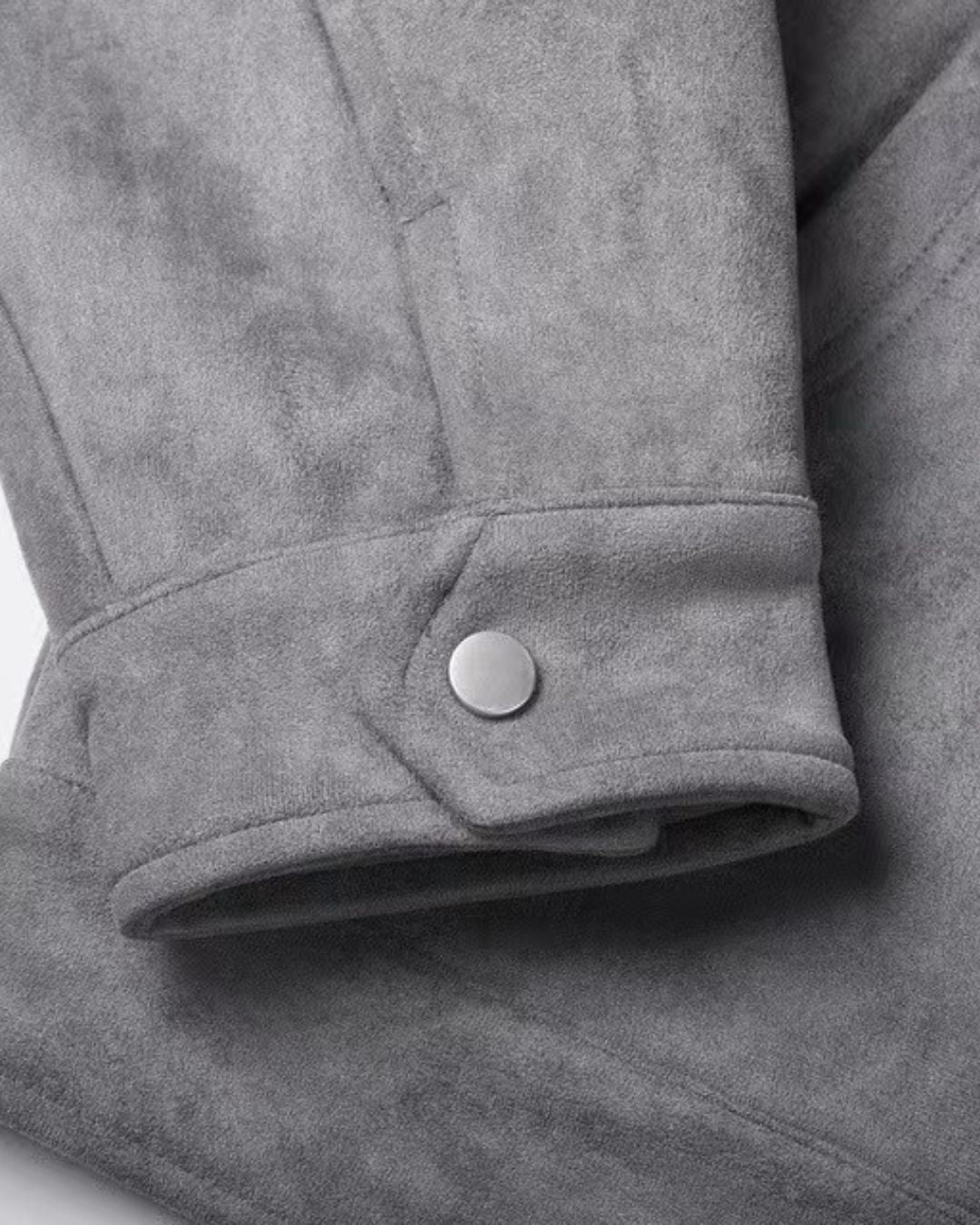 Close-up of a men's gray casual zip-up overshirt jacket sleeve cuff with a single silver snap button closure.