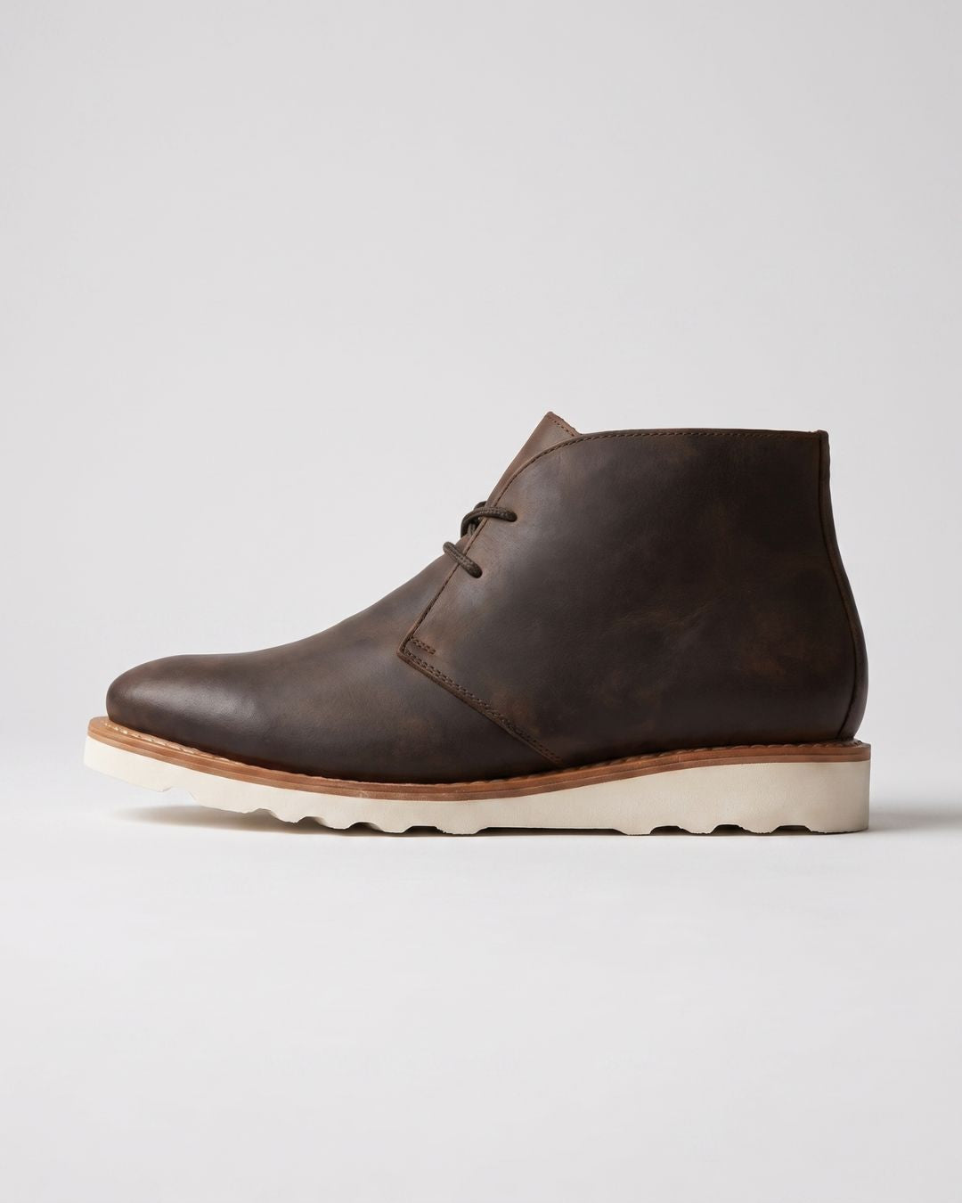 Dark brown faux leather chukka boots with a white chunky foam sneaker sole and lace-up ankle design.