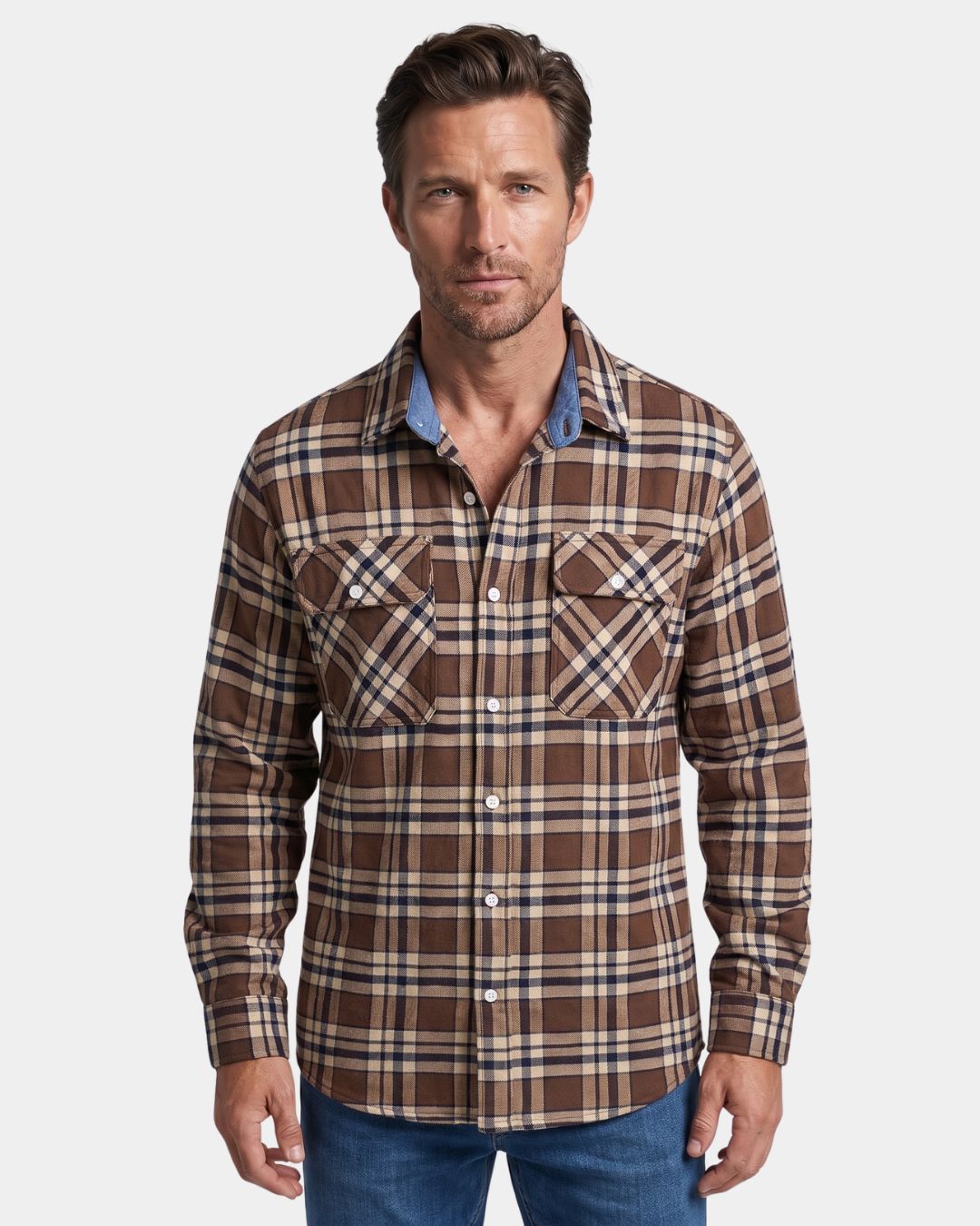 Man wearing a brown plaid flannel shirt with a button-front, two chest pockets, and a blue chambray collar lining.