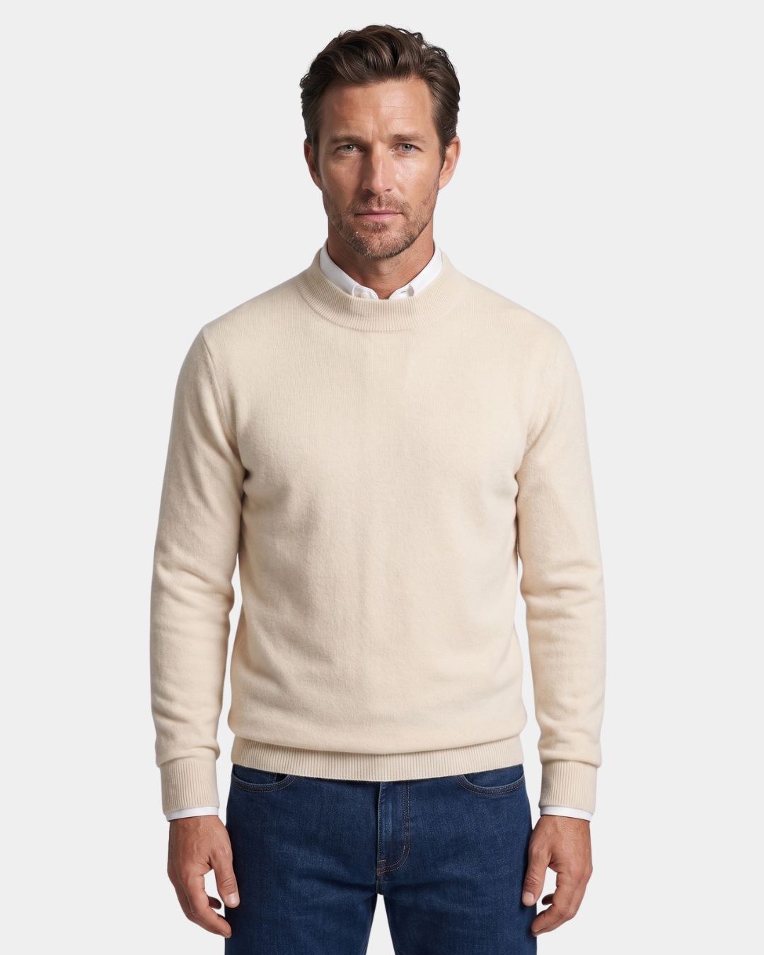 Man wearing an off-white 100% wool mock neck sweater with ribbed cuffs over a white collared shirt and blue jeans.