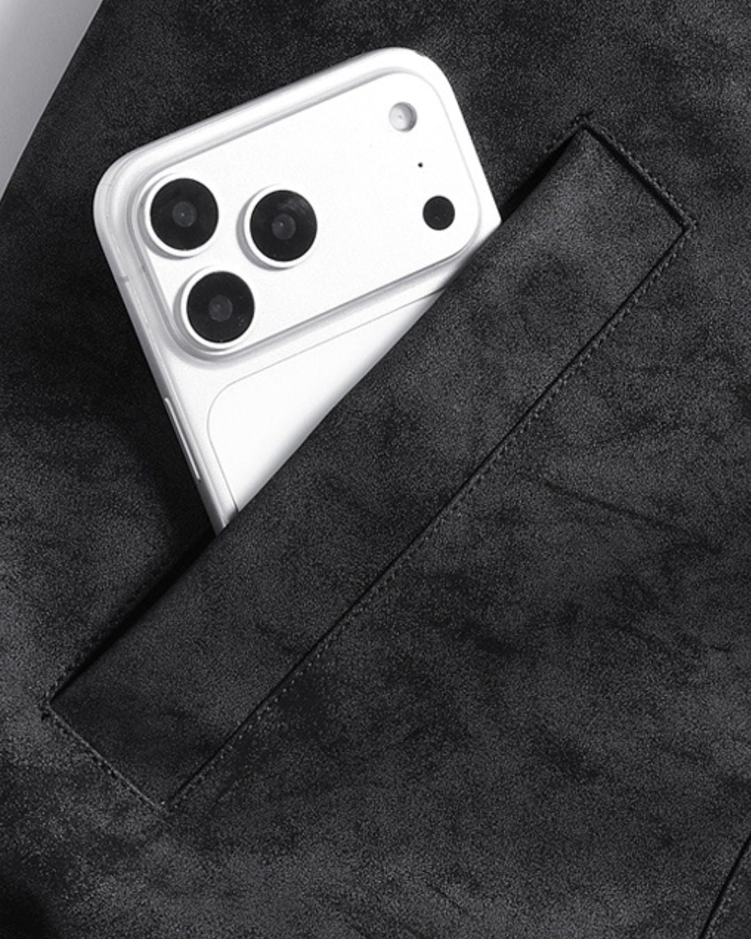 Close-up of black collared bomber jacket pocket holding a smartphone