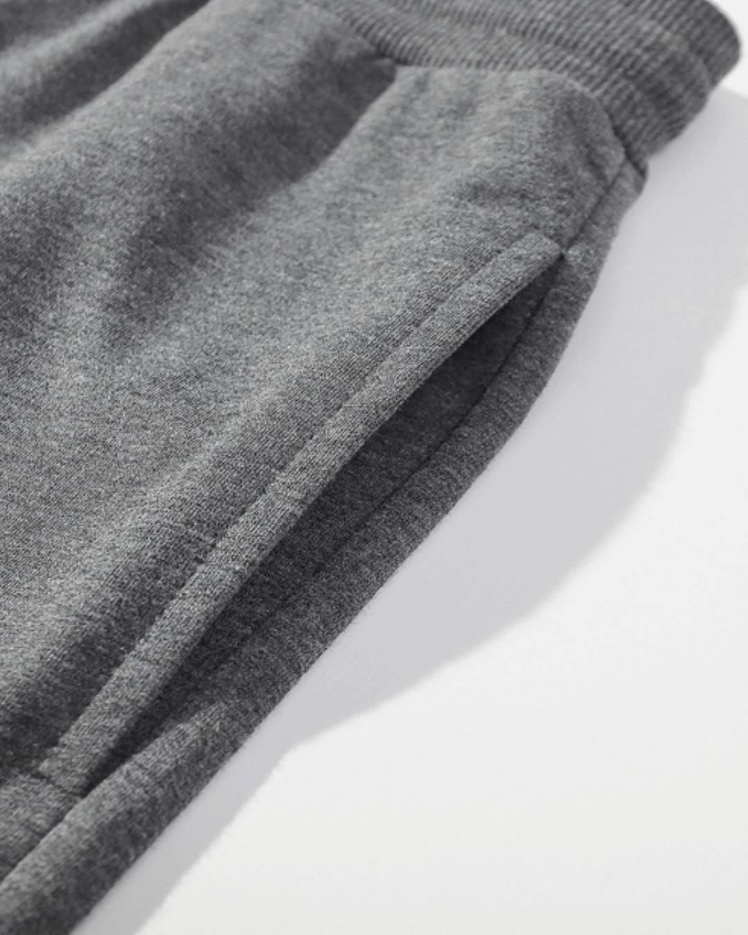 Close-up of charcoal grey cotton jogger sweatpants featuring a soft, washed texture and a side pocket detail.