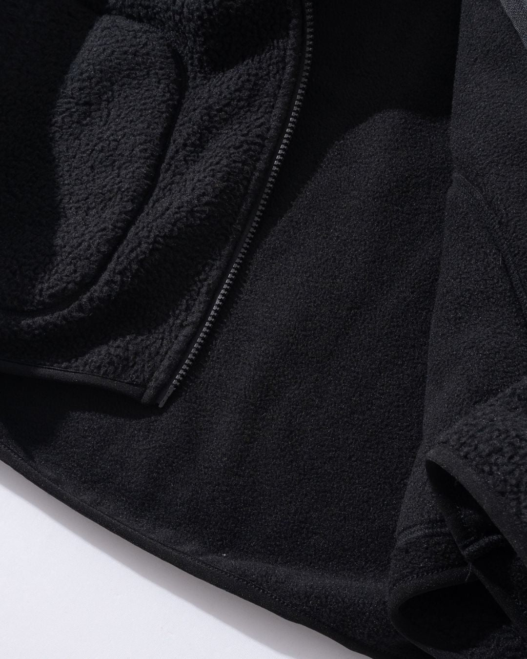 Close-up of a black men’s full-zip teddy jacket showing the textured sherpa fleece exterior and smooth fleece interior.
