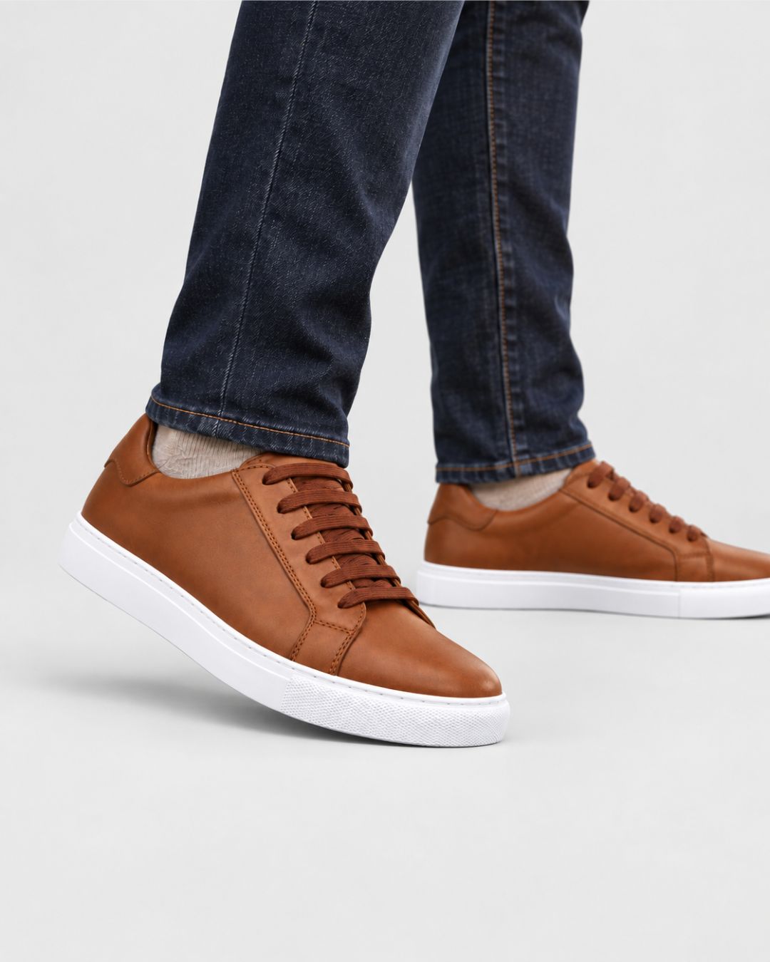 Men’s tan top-grain leather low-top dress sneakers with matching laces and a white rubber outsole.