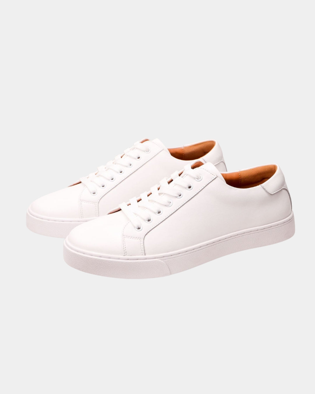 Minimalist white leather low-top dress sneakers with a lace-up design and durable rubber outsole.