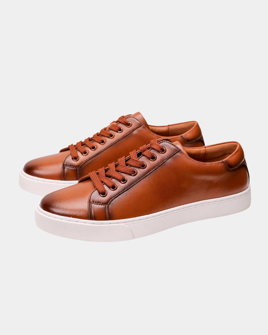 Cognac brown genuine leather low-top dress sneakers with matching laces and a clean white rubber outsole.