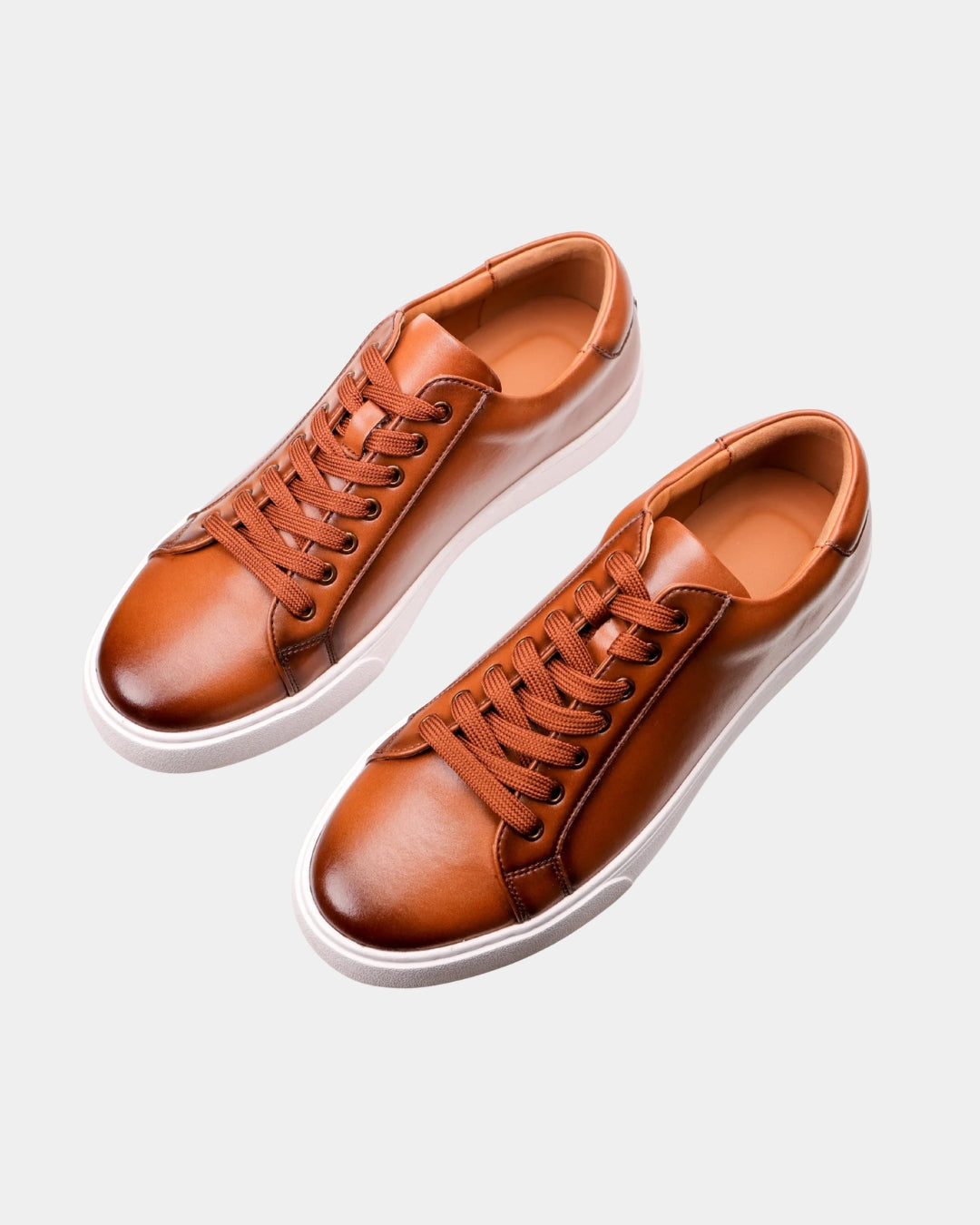 Cognac brown genuine leather low-top dress sneakers with matching laces and a clean white rubber outsole.