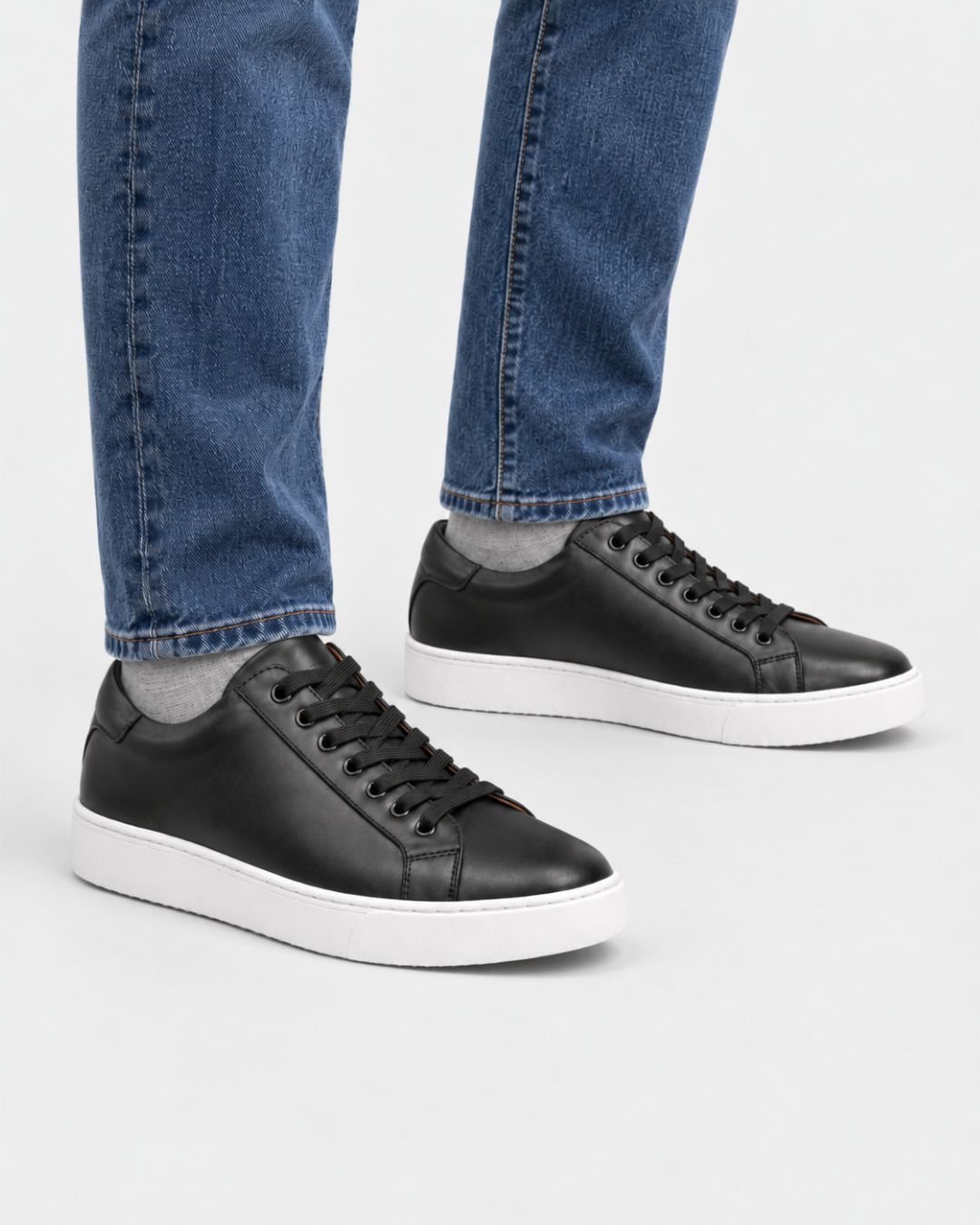 Men's black genuine leather low-top dress sneakers with black laces and a clean white rubber outsole.