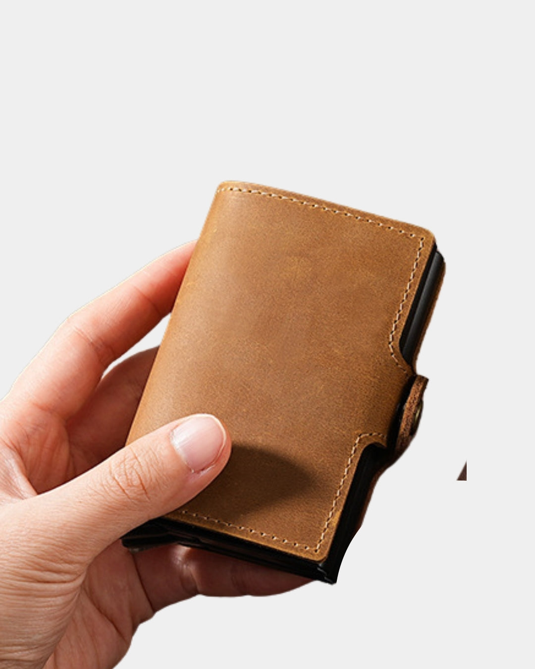 Compact tan genuine leather pop-up card wallet with a snap-button closure held in a hand.