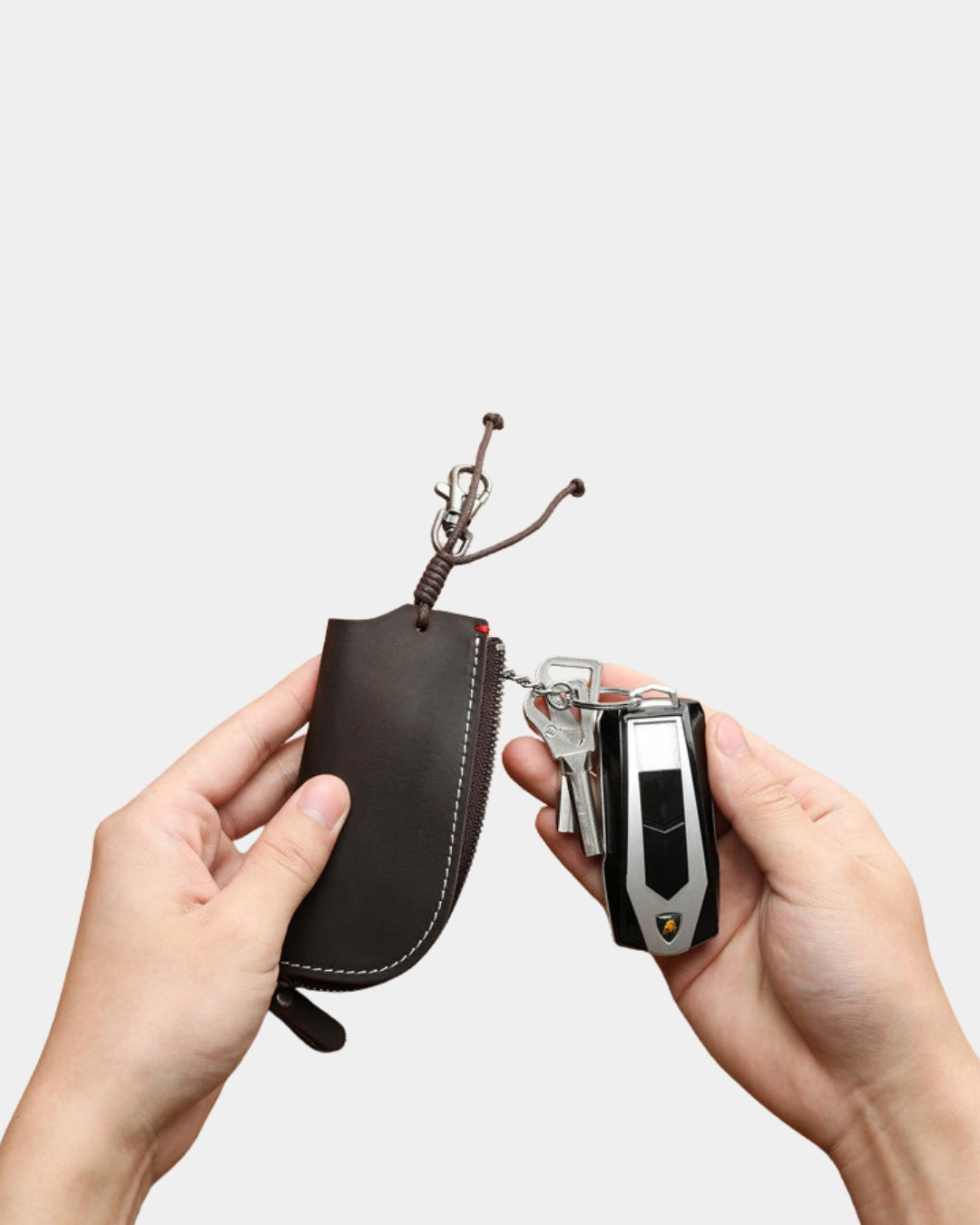Dark brown genuine cowhide leather key wallet with a metal clip, zipper closure, and car keys attached.
