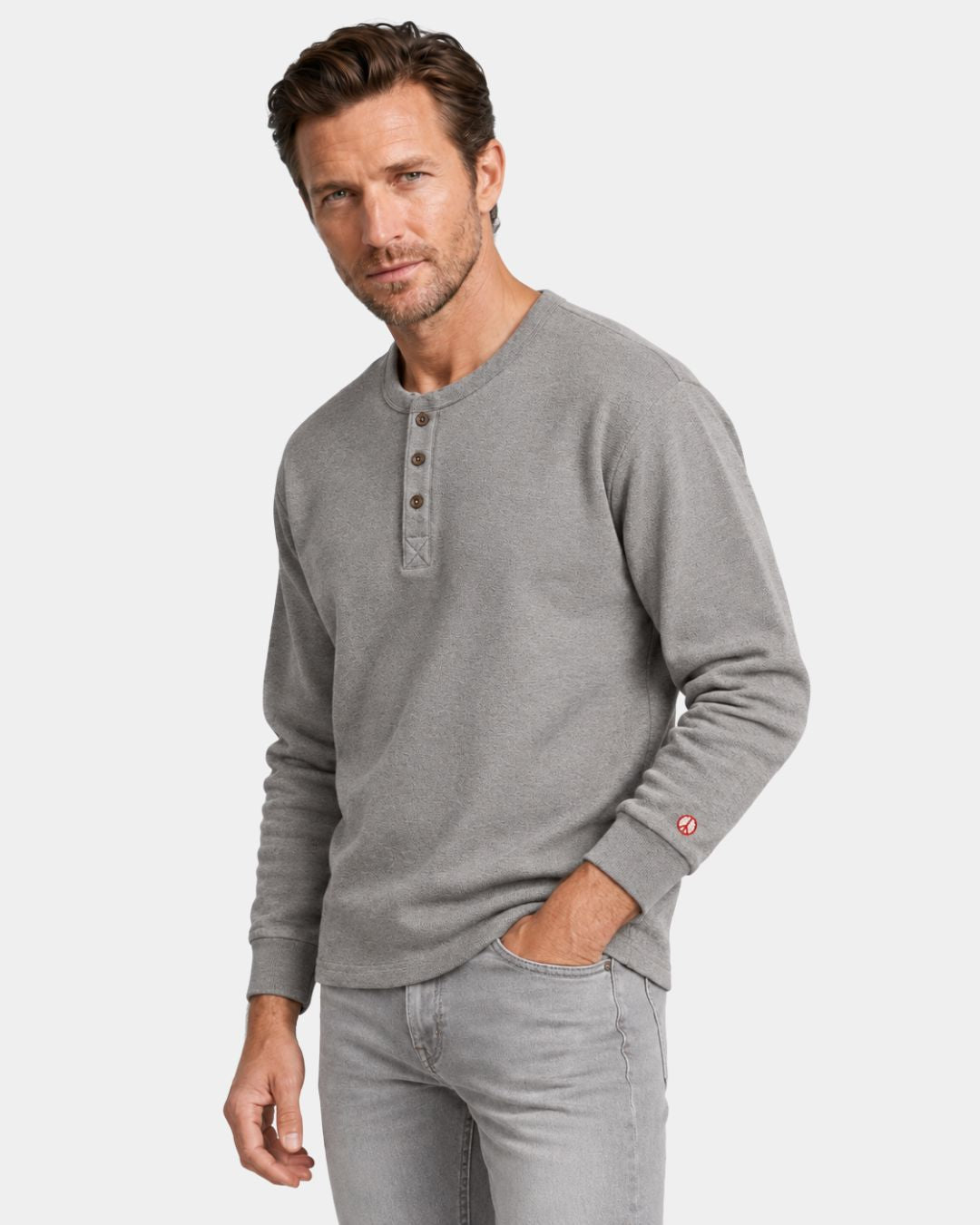 Man wearing a gray heavyweight cotton long-sleeve henley shirt with a three-button placket and red peace symbol on the cuff.