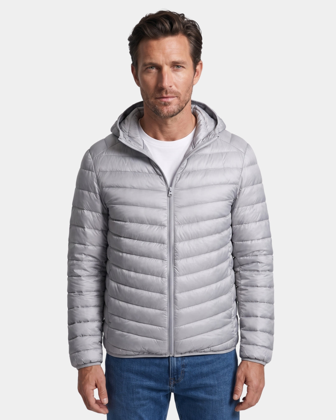 Man wearing a light grey, hooded, quilted puffer jacket with a full-zip front and lightweight nylon shell.