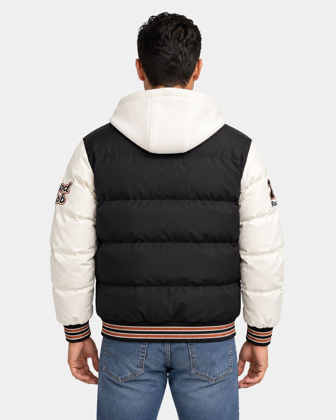 Back view of a black and white hooded varsity puffer jacket with embroidered patches and striped ribbed trim.