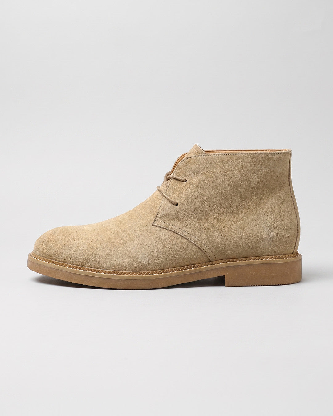 Side view of a beige suede men’s chukka boots with a two-eyelet lace-up design, square toe, and durable low-profile rubber sole.