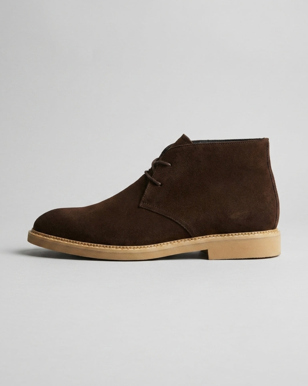 Dark brown suede men's chukka boots with a two-eyelet lace-up design and a flat, light-colored rubber sole.