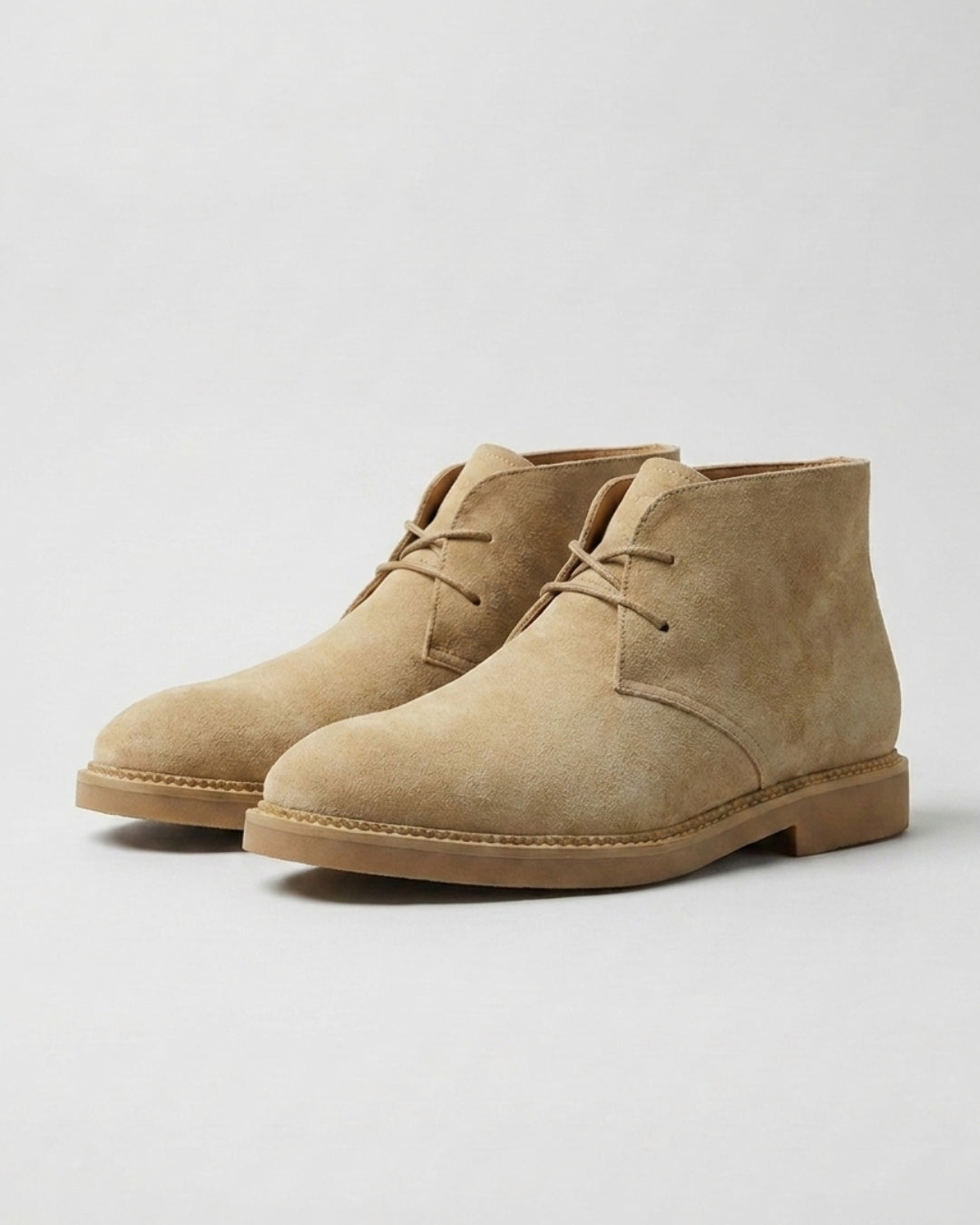 Beige suede men’s chukka boots with a two-eyelet lace-up design, square toe, and durable low-profile rubber sole.