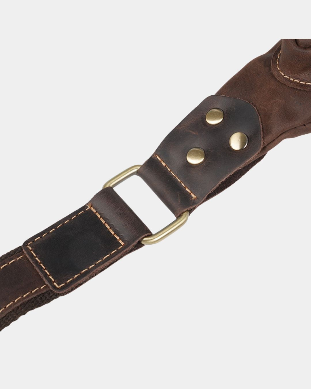 Close-up of a brown vintage leather sling bag strap featuring brass hardware, reinforced stitching, and metal rivets.