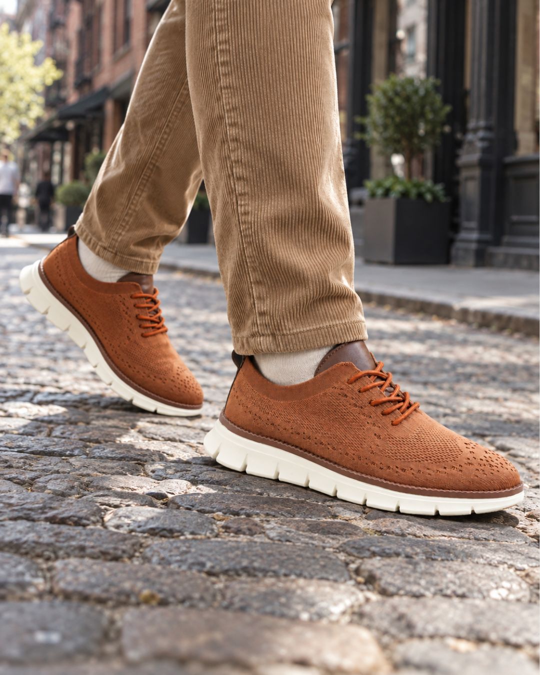 Tan breathable mesh dress sneakers with lace-up closure and white cushioned EVA soles worn with corduroy trousers.