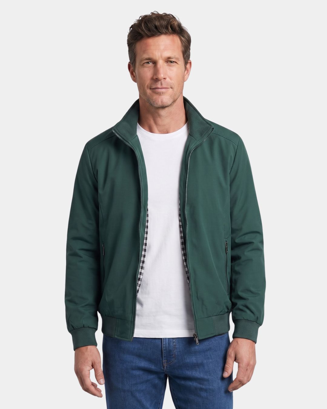 Man wearing a dark green lightweight Harrington jacket with a stand collar, zip front, and checked lining.