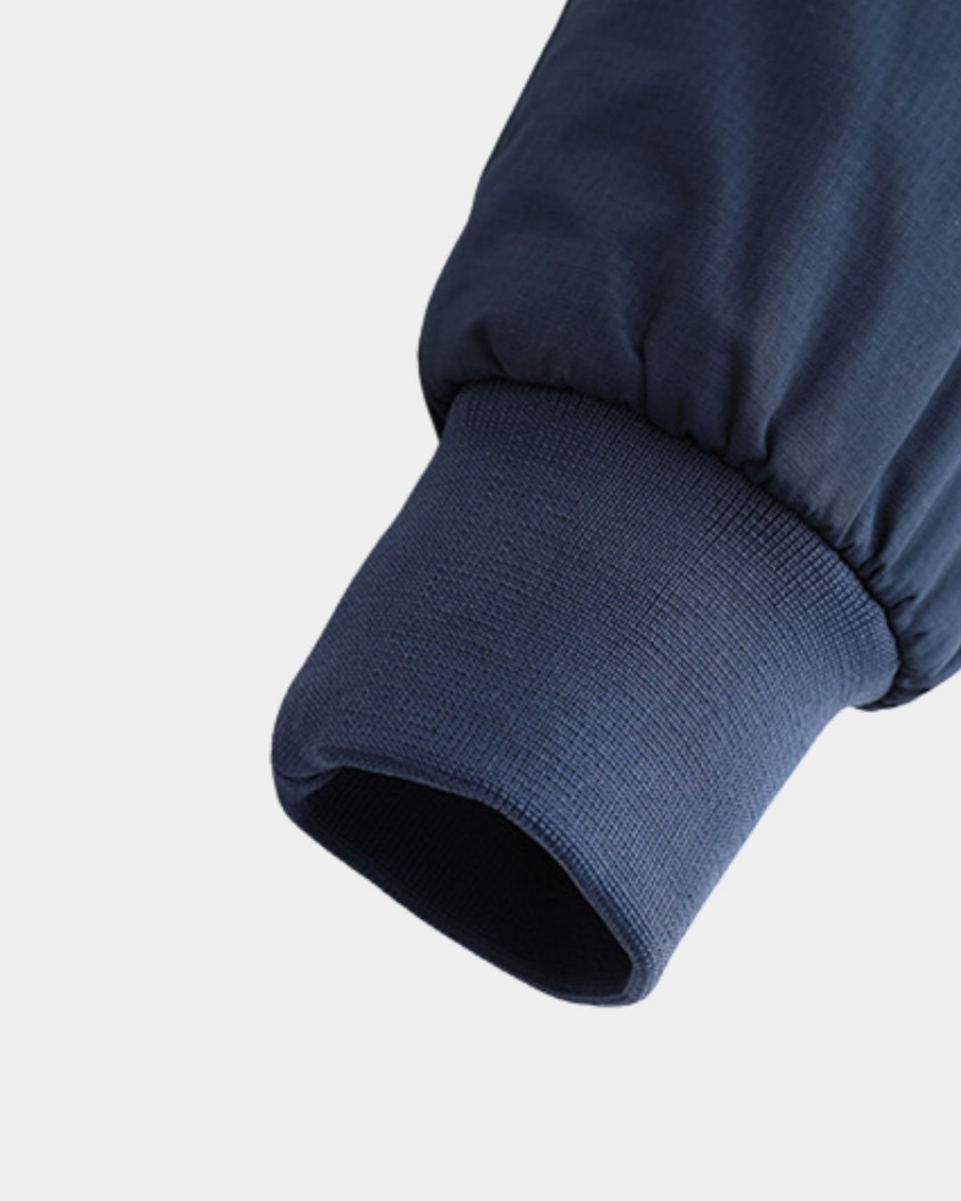 Close-up of a navy blue lightweight Harrington jacket sleeve featuring a comfortable ribbed knit cuff.