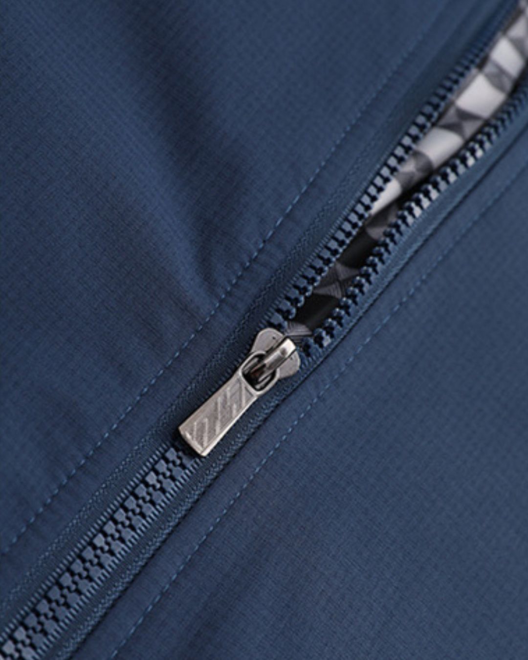 Close-up of a blue lightweight Harrington jacket featuring a metal zip front and a traditional checked inner lining.