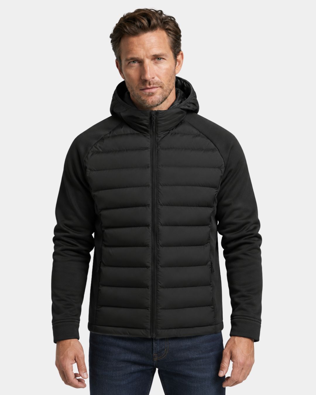 Man wearing a black lightweight hybrid puffer jacket with a quilted body, smooth sleeves, and an attached hood.