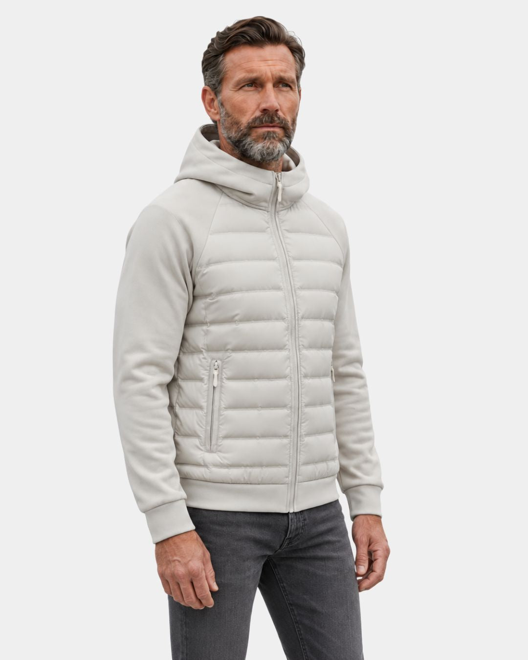 Beige men's hybrid puffer jacket with a quilted down body, knit sleeves, hood, and zip pockets on a light background.