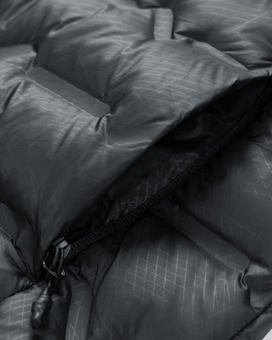 Close-up of a black quilted puffer jacket featuring a durable grid-patterned fabric and a zippered pocket.