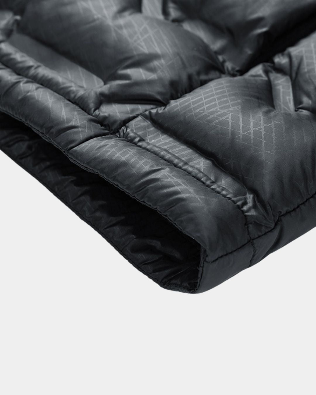 Close-up of a black quilted puffer jacket sleeve featuring a subtle geometric grid pattern on the waterproof fabric.