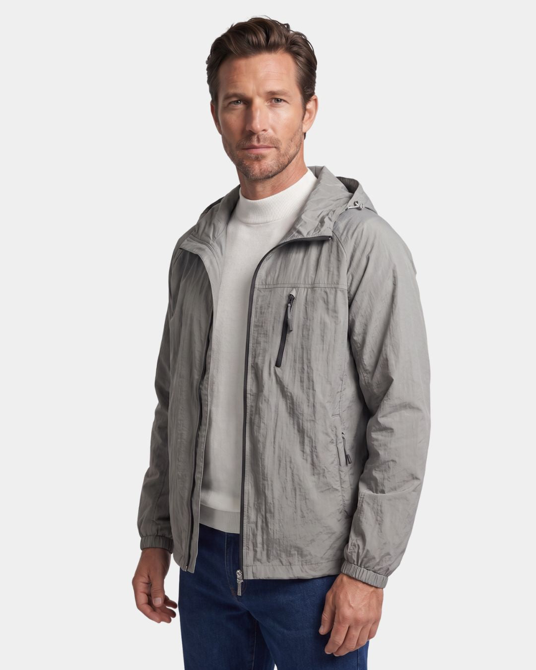 Man wearing a grey lightweight, hooded waterproof windbreaker with a zippered chest pocket and athletic fit.