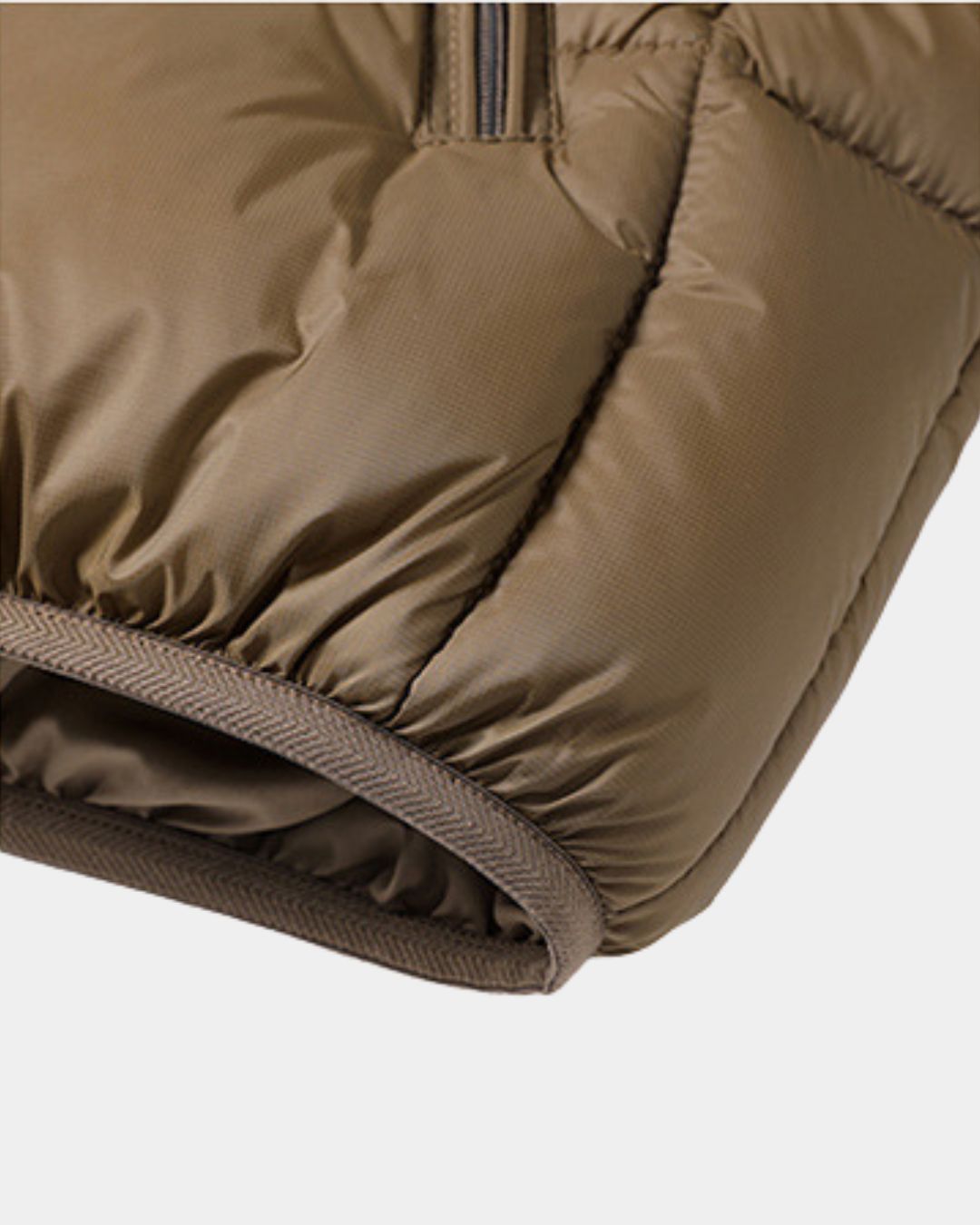 Close-up of a brown padded winter puffer jacket featuring quilted polyester fabric and a zippered chest pocket.
