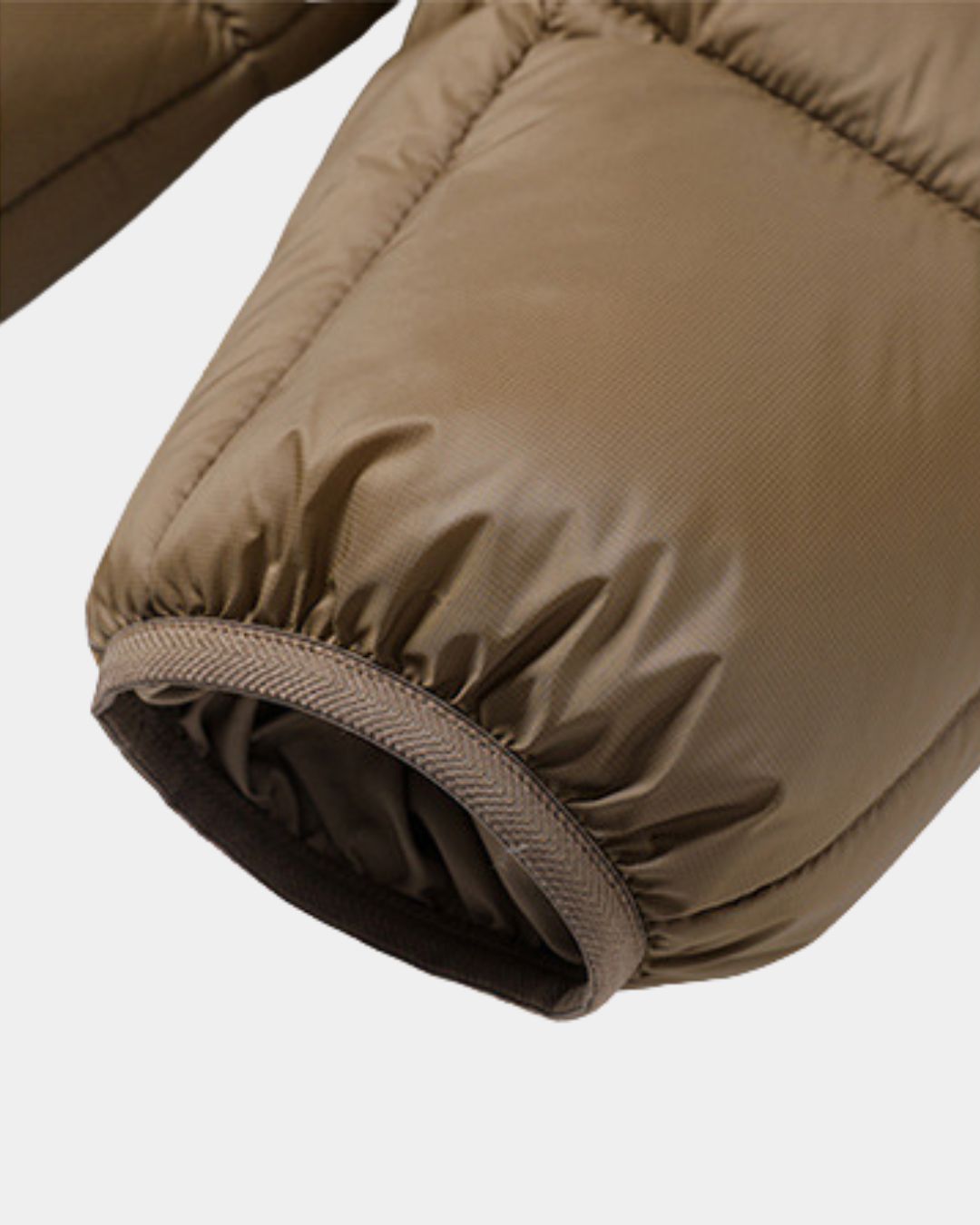 Close-up of a brown padded winter puffer jacket sleeve featuring a durable polyester shell and elasticized cuff.