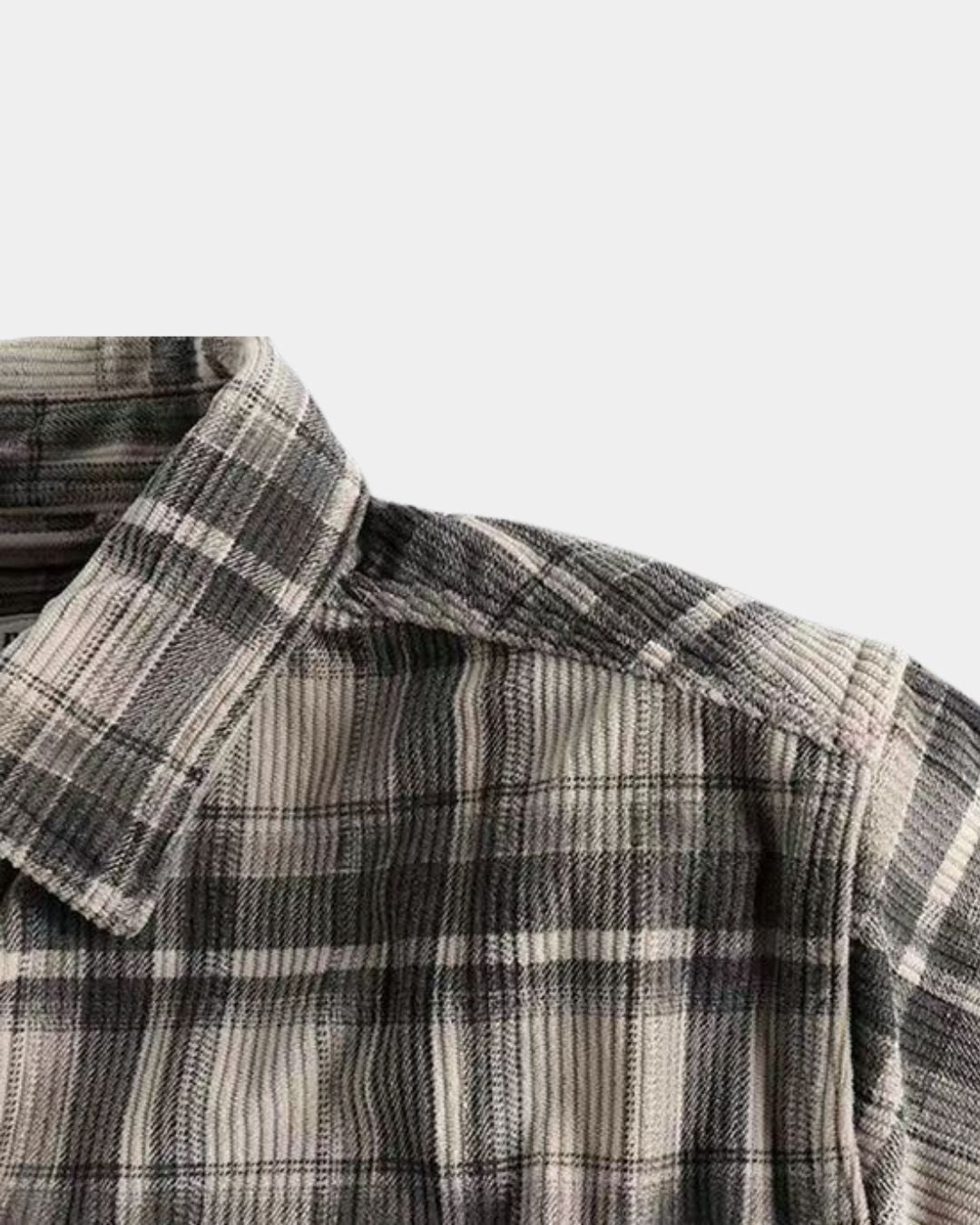 Close-up of a men’s grey and white plaid corduroy long sleeve shirt with a classic spread collar.