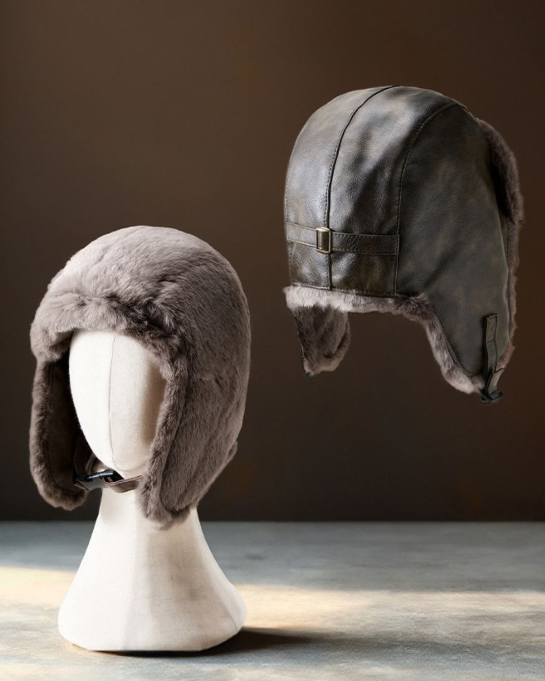 Reversible men's trapper hat showing both the plush grey fleece side and the brown waterproof leather-look exterior.