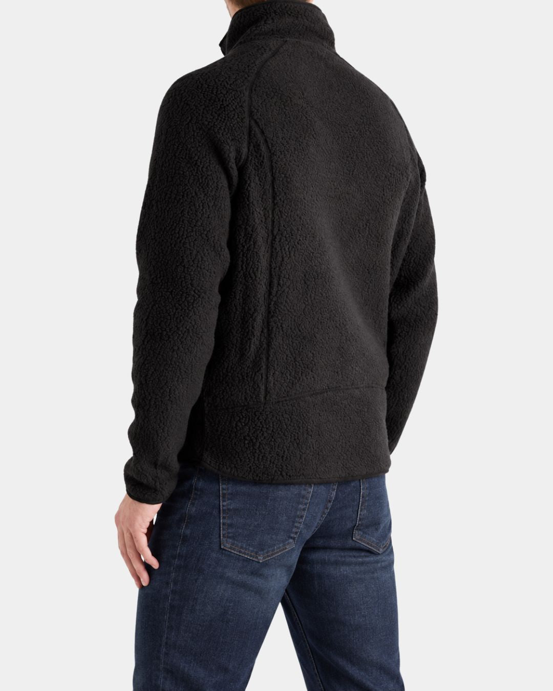 Back view of a men’s black teddy sherpa fleece jacket with a stand collar, worn with dark blue denim jeans.