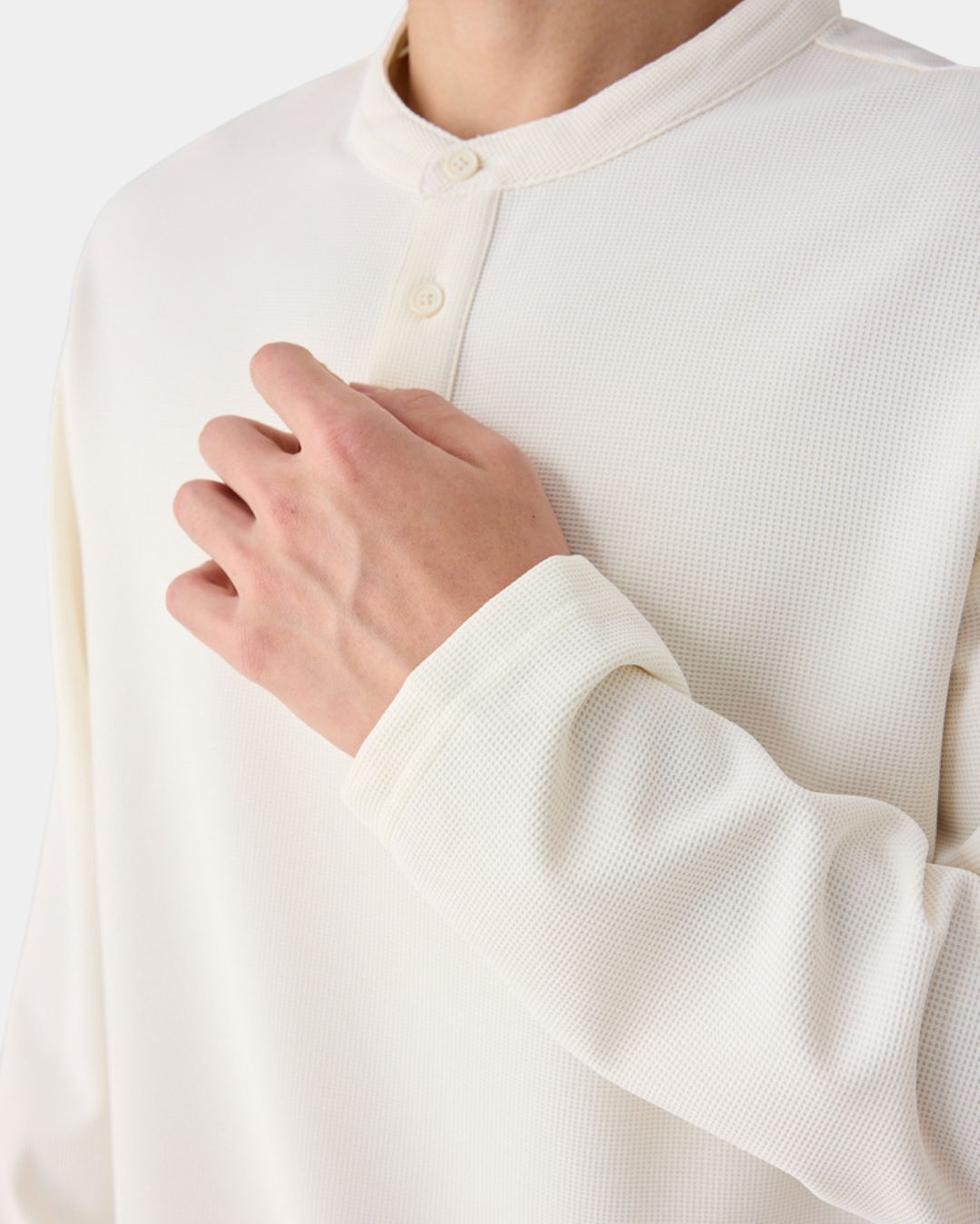 Off-white long sleeve henley shirt in a textured waffle knit with a band collar and three-button placket.
