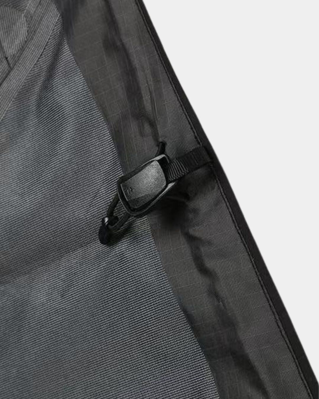 Close-up of a black waterproof hiking jacket featuring a durable grid-pattern shell and an adjustable drawstring toggle.